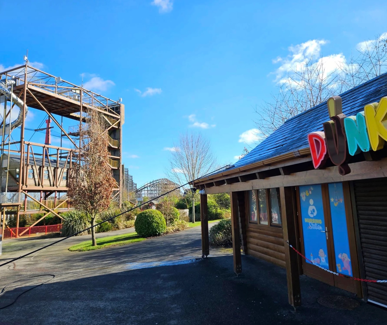 Exterior cleaning at Tayto Park, County Meath — hose line out to the park buildings with the rides behind